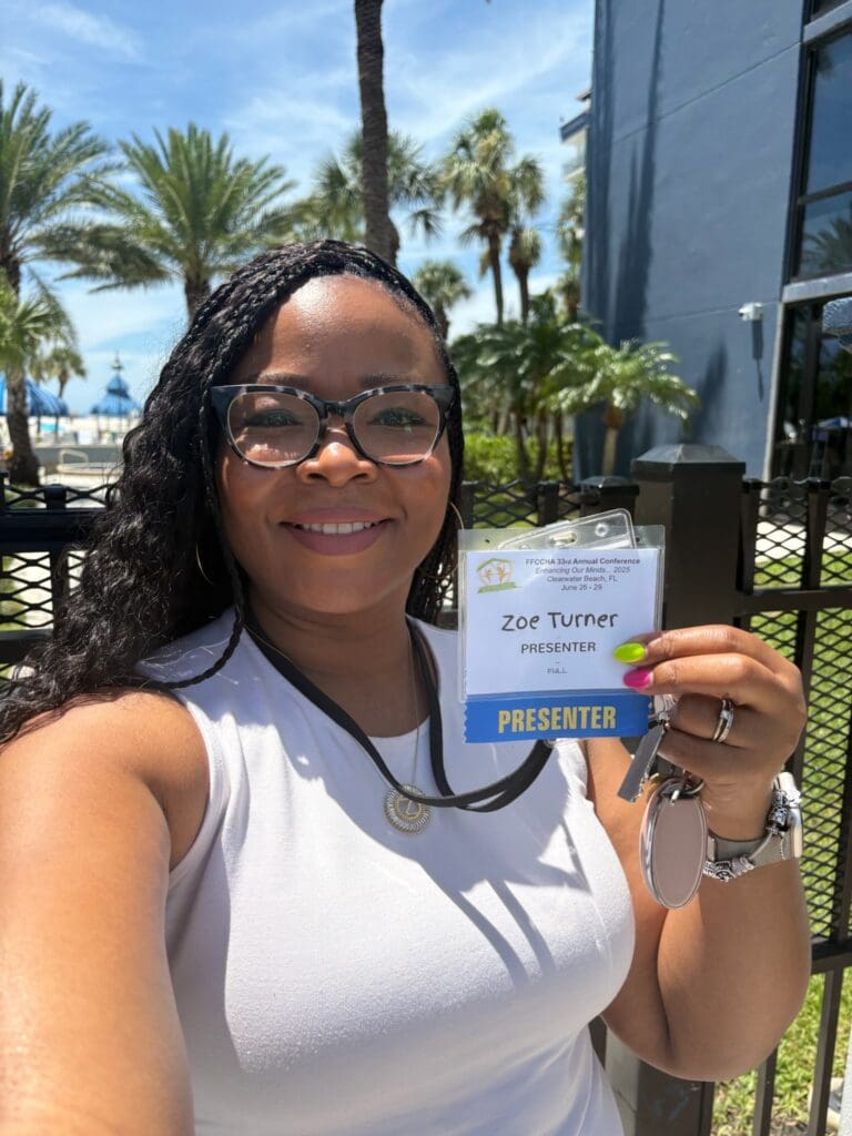 Zoe holding up her conference presenter lanyard